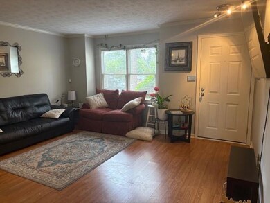 Living room with wood finished floors, crown moldi