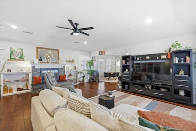Living room featuring dark wood finished floors, a fireplace, ceiling fan, and recessed lighting