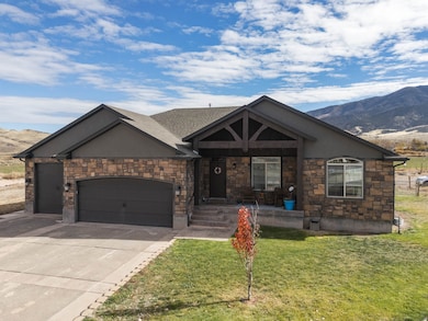 View of front facade with a mountain view, an attached garage, stone siding, and concrete driveway