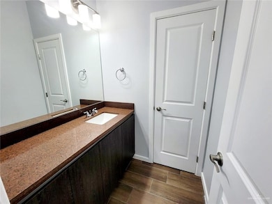 Bathroom featuring wood tiled floors, baseboards, and vanity