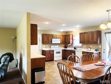 Kitchen featuring light countertops, white appliances, decorative light fixtures, recessed lighting, and a chandelier