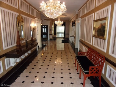 Corridor with an inviting chandelier, crown molding, and tile patterned floors