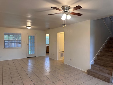 Unfurnished room with stairs, ceiling fan, and li
