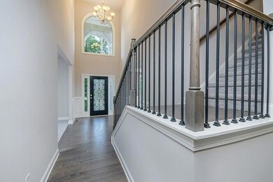 Foyer entrance featuring a towering ceiling, wood finished floors, stairs, a notable chandelier, and baseboards