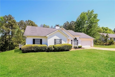 View of front facade featuring a chimney, an attached garage, driveway, and a front lawn