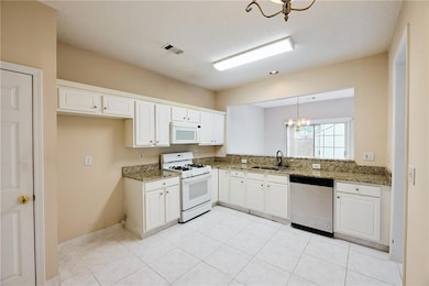 Kitchen featuring white appliances, a chandelier, 