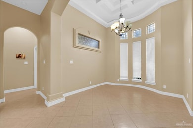 Unfurnished room featuring arched walkways, light tile patterned flooring, a high ceiling, and a chandelier