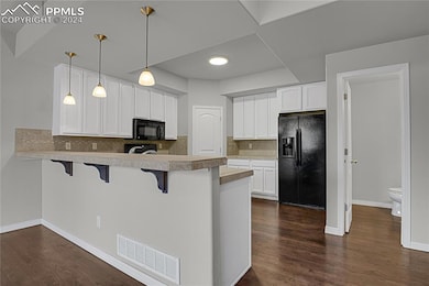 Kitchen featuring dark wood-type flooring, black a