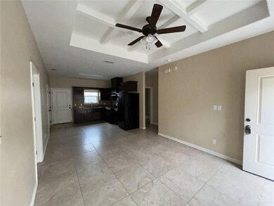 Unfurnished living room featuring a ceiling fan, a sink, a tray ceiling, baseboards, and coffered ceiling