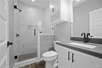 Bathroom featuring vanity, toilet, wood finished floors, and a stall shower