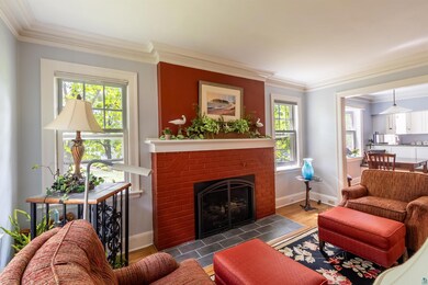 Living room featuring dark wood-style floors, crown molding, a fireplace, and a healthy amount of sunlight