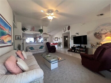 Living area featuring a ceiling fan and vaulted ce