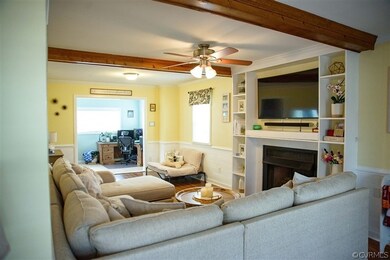 Living room featuring beamed ceiling, ceiling fan,