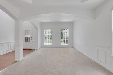 Unfurnished living room with carpet flooring and arched walkways