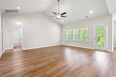 Unfurnished room featuring a ceiling fan, lofted ceiling, and wood finished floors