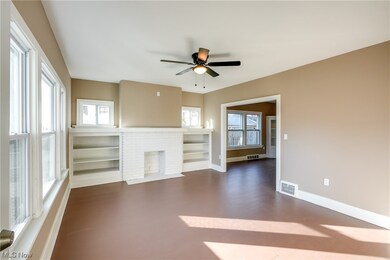 Unit 1 - Living room with built in features, a brick fireplace, and ceiling fan.  New windows and new light fixtures (2023).