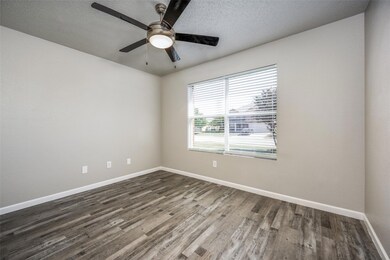 Empty room featuring a textured ceiling, wood-type flooring, and ceiling fan
