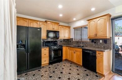 Granite countertops and backsplash and wood cabinets are featured in the kitchen.