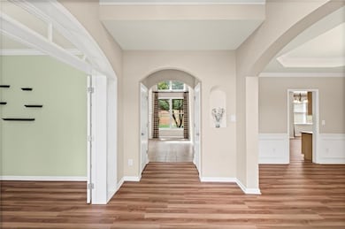 Entryway featuring healthy amount of natural light, arched walkways, light wood-type flooring, a chandelier, and crown molding