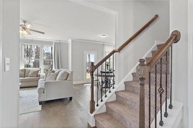 Stairway featuring baseboards, ornamental molding, wood finished floors, and a ceiling fan