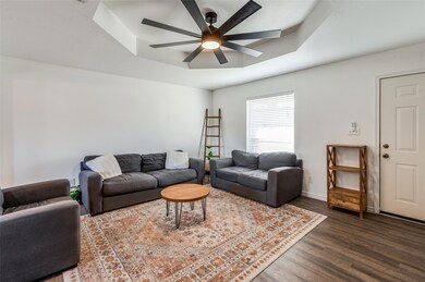 Living room featuring ceiling fan, a tray ceiling, and dark hardwood / wood-style flooring