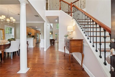 Foyer featuring wood finished floors, an inviting chandelier, a high ceiling, and baseboards