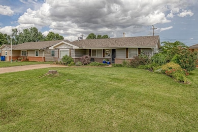 Ranch-style home featuring brick siding, a front yard, a porch, and a shingled roof