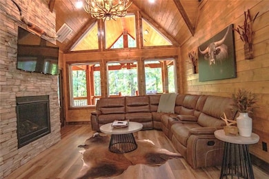 Living room with a stone fireplace, wooden ceiling