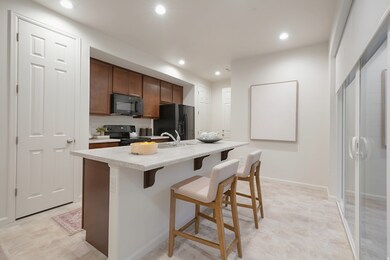 Kitchen with light countertops, a kitchen bar, black appliances, recessed lighting, and a center island with sink