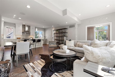 Living room with healthy amount of natural light, dark wood-style flooring, and recessed lighting