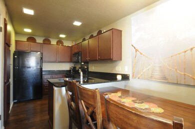 Kitchen featuring black appliances, a peninsula, dark wood finished floors, and brown cabinetry