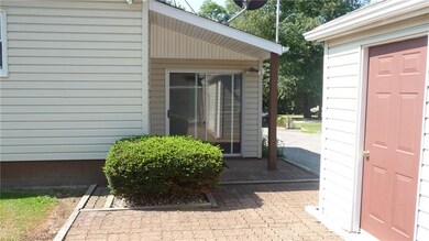 Rear entry of sunroom has a patio door and overhan