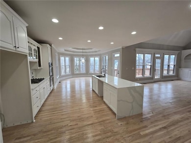 Kitchen with white cabinetry, light stone countert