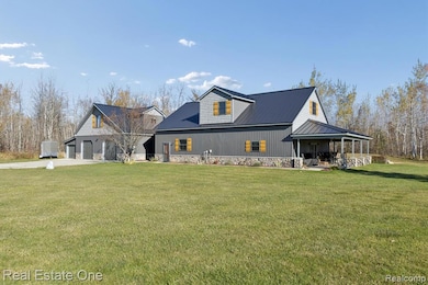 Rear view of house featuring a yard, a metal roof, a garage, and a porch