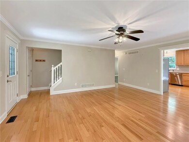 Unfurnished living room featuring light wood-style floors, ornamental molding, stairs, and ceiling fan