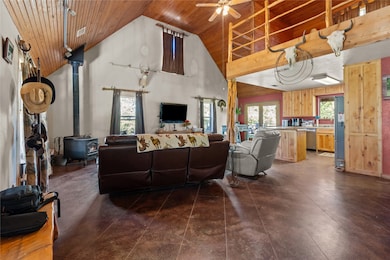 Living area with wood ceiling, a wood stove, high vaulted ceiling, healthy amount of natural light, and ceiling fan