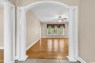 Corridor with decorative columns, arched walkways, baseboards, wood finished floors, and a textured ceiling