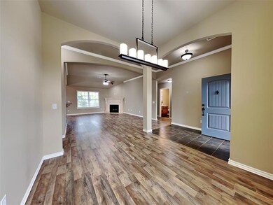 Unfurnished living room with wood finished floors, arched walkways, a fireplace, crown molding, and ceiling fan