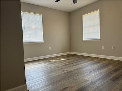 Empty room featuring healthy amount of natural light, wood finished floors, and a ceiling fan