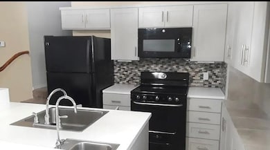 Kitchen with black appliances, backsplash, light 