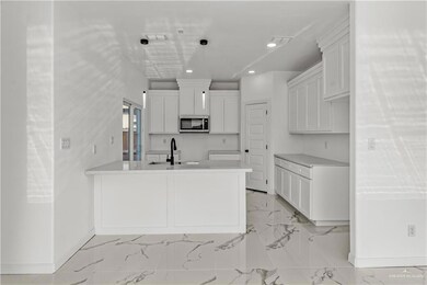 Kitchen featuring white cabinetry, sink, light tile floors, and pendant lighting
