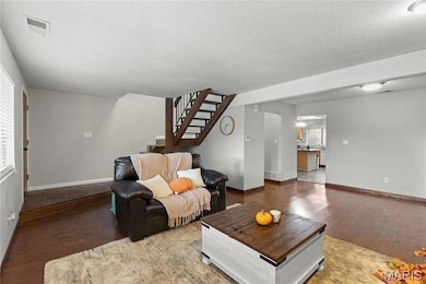 Living area with wood finished floors, stairway, and a textured ceiling