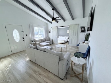 Living room with ceiling fan, light wood-style floors, and a barn door