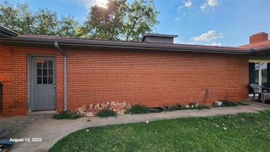 View of property exterior with brick siding, a yard, and a chimney