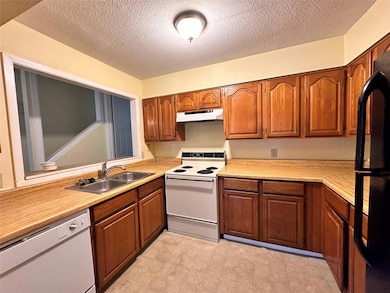 Kitchen featuring white appliances, a sink, under