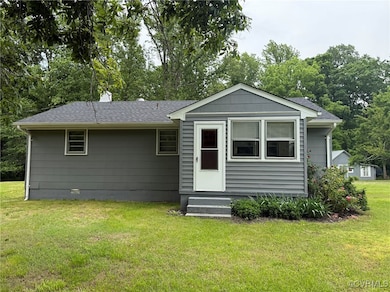 Back of property with entry steps, a lawn, and a s