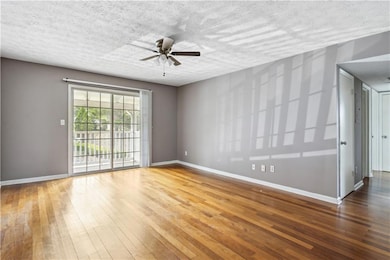 Spare room featuring hardwood / wood-style floors, a ceiling fan, and a textured ceiling