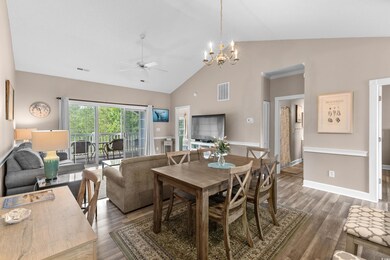 Dining space with ceiling fan, wood finished floors, a chandelier, and high vaulted ceiling