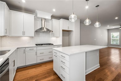 Kitchen featuring wall chimney exhaust hood, stainless steel appliances, recessed lighting, light wood-type flooring, and decorative backsplash