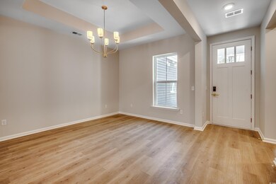 Entrance foyer featuring a raised ceiling, a chandelier, and light wood-style floors